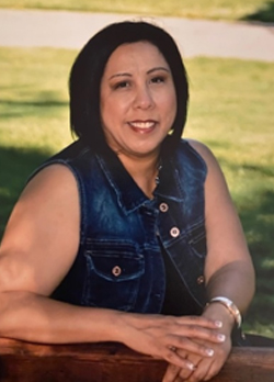 Woman with short black hair wearing a jean vest